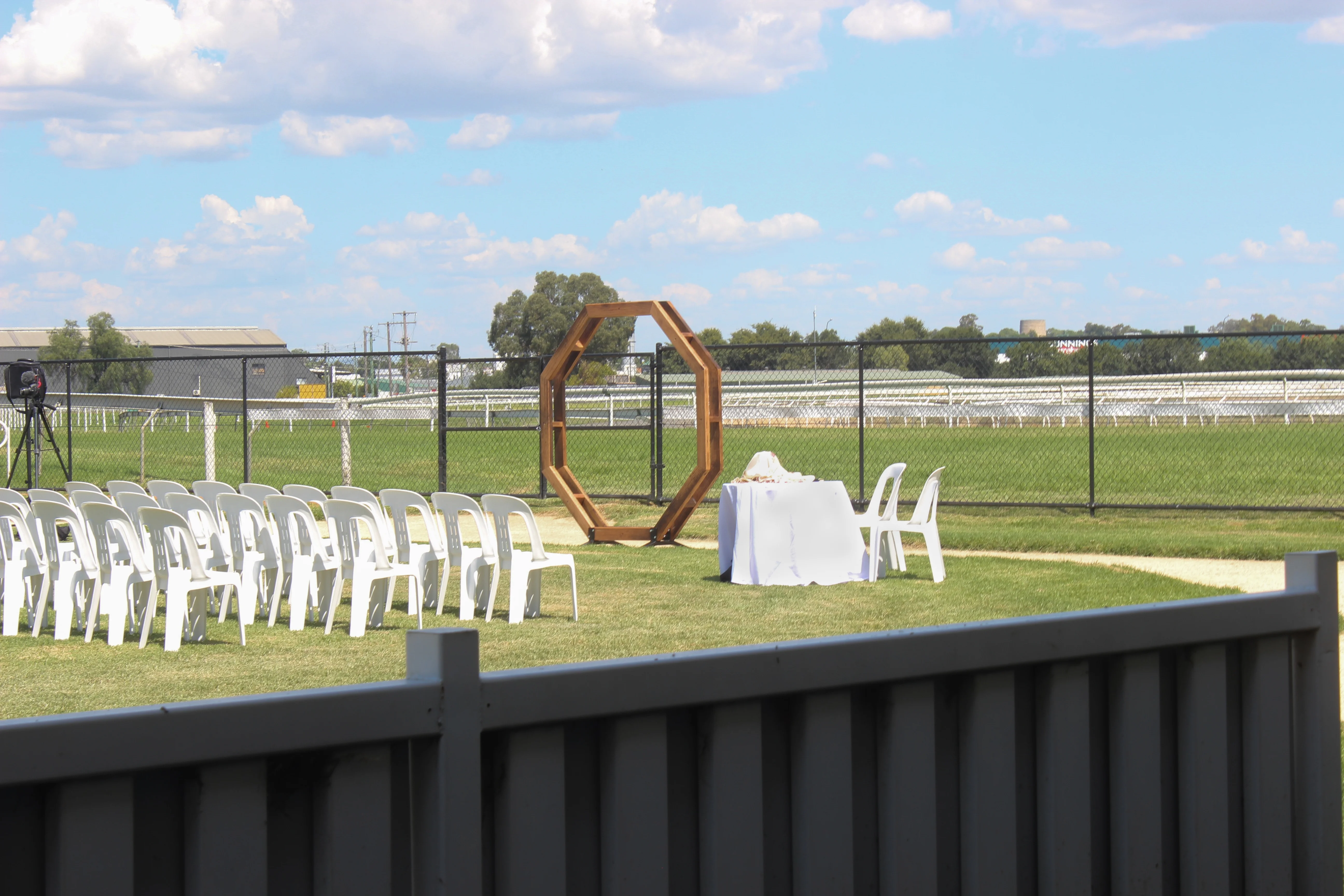 Outdoor wedding ceremony setup with wooden arch and white chairs across NSW