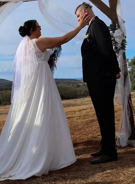 Bride tenderly wiping tears from groom at the altar